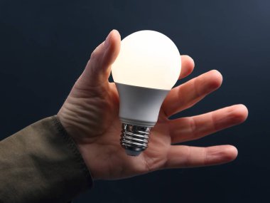 Koyu arka plan üzerinde insan elinde yeni LED lamba dahildir