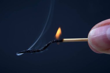 Koyu arka plan üzerinde elinde yanan ve ahşap Sigara maç