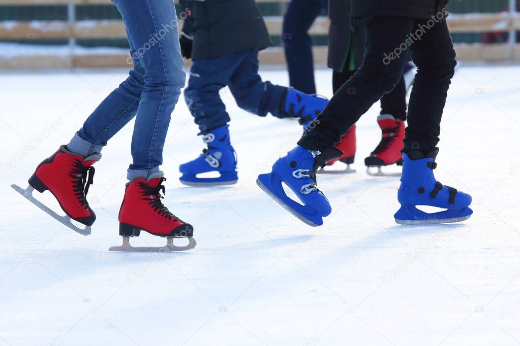 feet of different people skating on the ice rink