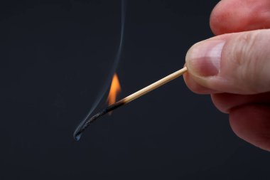 Koyu arka plan üzerinde elinde yanan ve ahşap Sigara maç