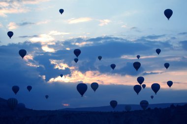 Birçok yolcu balonu bulutlarda şafak vakti arka planda uçar.