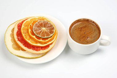 Kurutulmuş dilim çeşitli narenciye ve beyaz bir fincan sade kahve