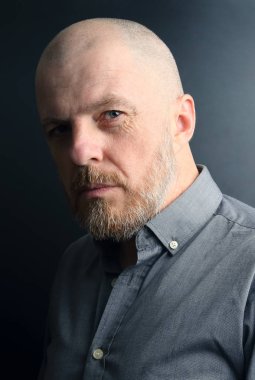 karanlık bir arka plan üzerinde sakallı bir adam portresi