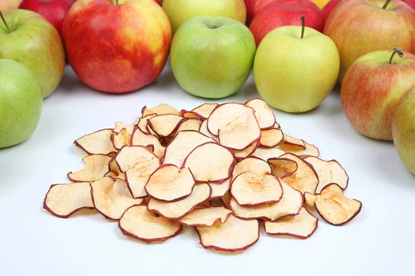 Dried Apple slices surrounded by fresh apples on white background