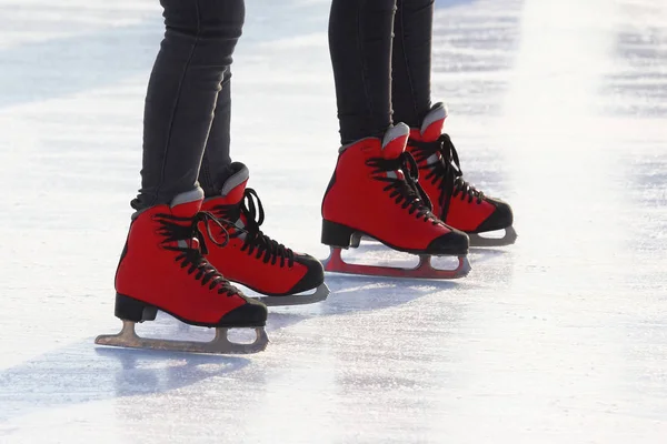 feet in red skates on an ice rin