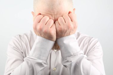 Beyaz arka plan yüzünde üzgün adam elleriyle kapalı