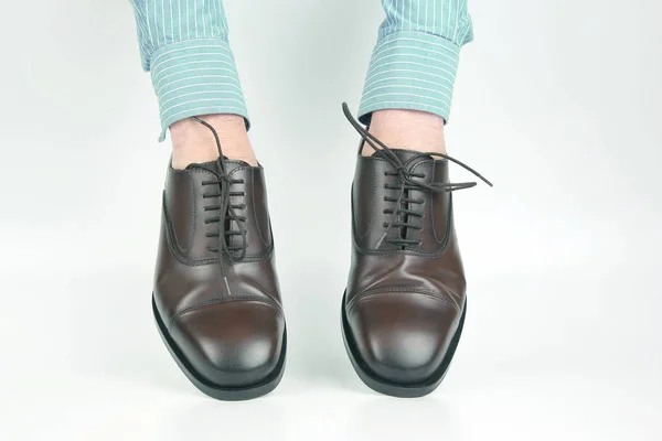 Klassiska bruna skor bärs på händerna på en vit bakgrund — Stockfoto