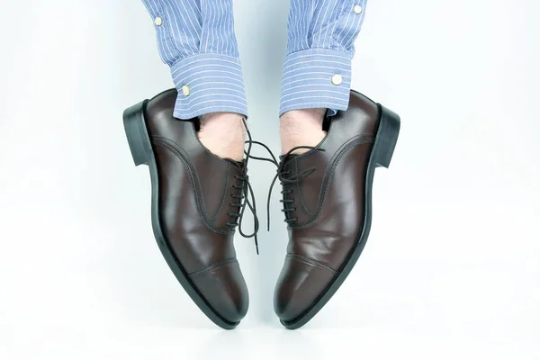 Classiche scarpe marroni indossate sulle mani su sfondo bianco — Foto Stock