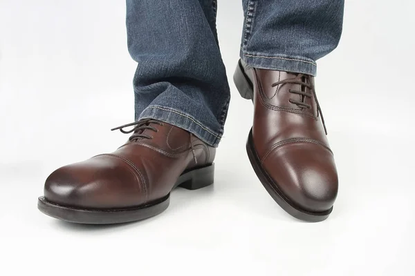 Mężczyzna nogi w dżinsy i brązowy klasyczne buty na białym tle — Zdjęcie stockowe