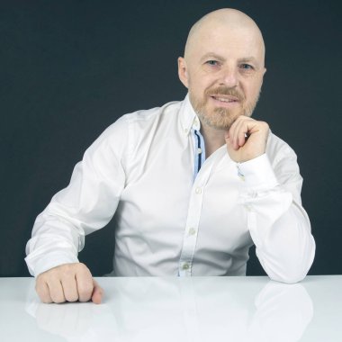 beyaz masada oturan beyaz gömlek mutlu sakallı adam