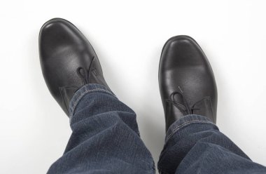 Beyaz arka planda kot pantolon ve siyah klasik ayakkabı erkek bacakları