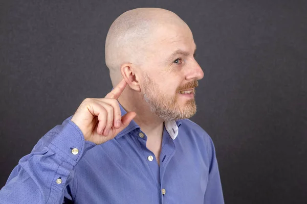 Бородатый человек указывает пальцем на его ухо — стоковое фото