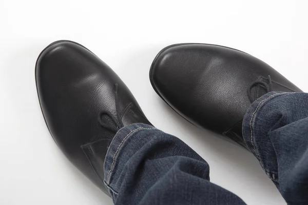 Männerbeine in Jeans und schwarzen klassischen Schuhen auf weißem Hintergrund — Stockfoto