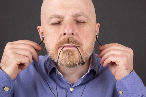 bearded man wants to listen to music through vacuum headphones