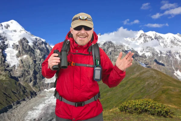 Счастливый путешественник с биноклем в руке на заснеженной горе — стоковое фото