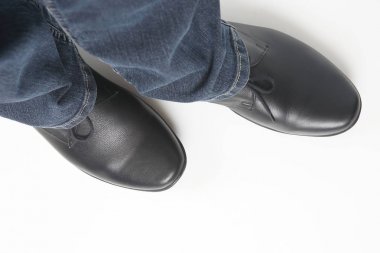 Beyaz arka planda kot pantolon ve siyah klasik ayakkabı erkek bacakları