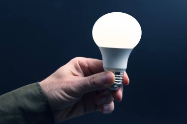 Koyu arka plan üzerinde insan elinde yeni LED lamba dahildir