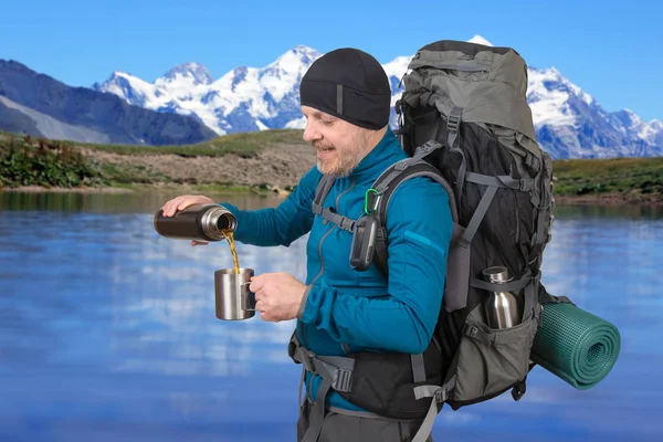 Happy man traveler pours tea in a mug on the background of beaut — Stock Photo, Image