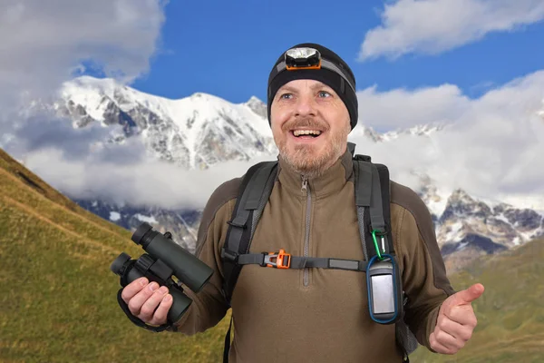 Счастливый путешественник с биноклем в руке на заснеженной горе — стоковое фото