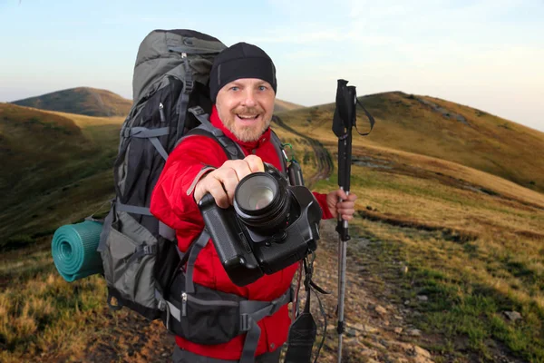 Извилистая дорога в горах Счастливый бородатый турист с камерой , — стоковое фото