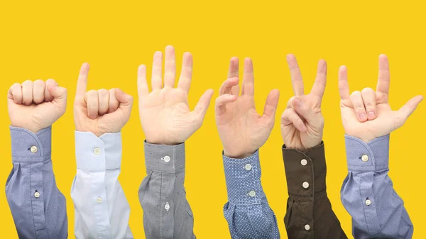 Raised hands of different men on yellow background — Stock Photo, Image