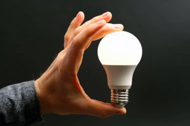 Koyu arka plan üzerinde insan elinde yeni LED lamba dahildir