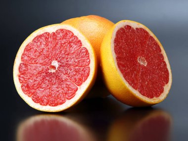 Narenciye. Dilimlenmiş ve koyu bir arka plan üzerinde bütün greyfurt