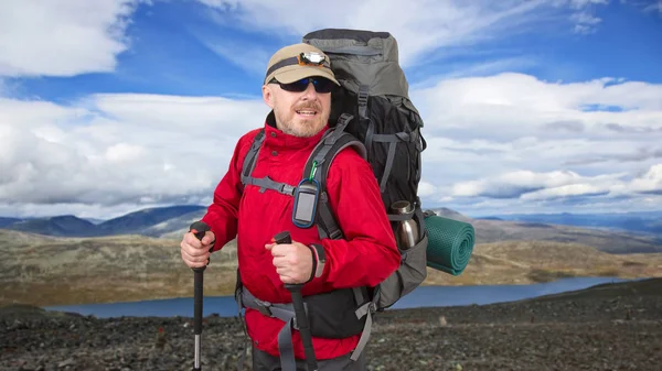 En lykkelig mannlig turist med ryggsekk ferdes i høylandet – stockfoto