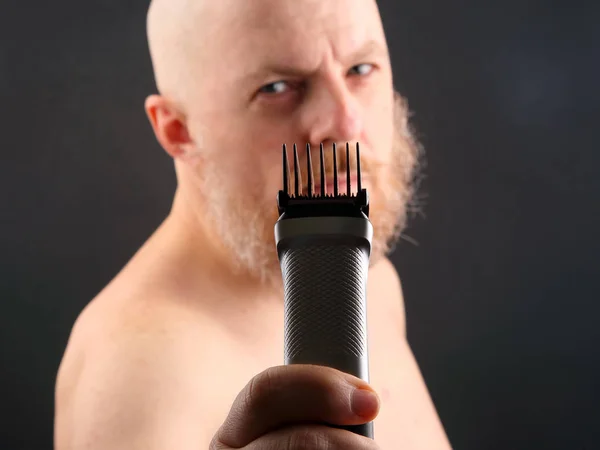 Bearded man with trimmer to adjust beard in hand — Stock Photo, Image