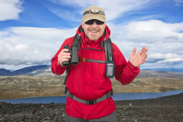 Счастливый человек путешественник с биноклем в руке на горы backgrou — стоковое фото