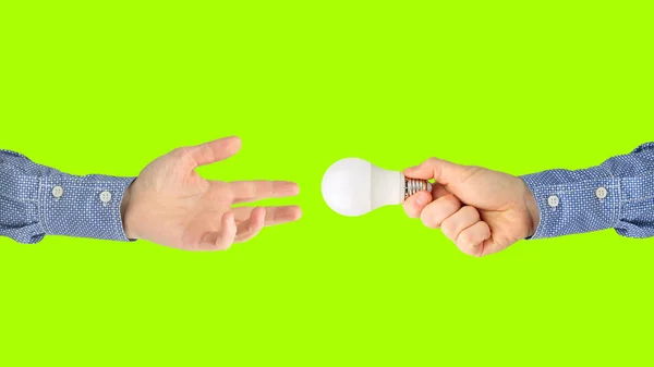 Dwie ręce z lampką LED na jasnym zielonym tle — Zdjęcie stockowe