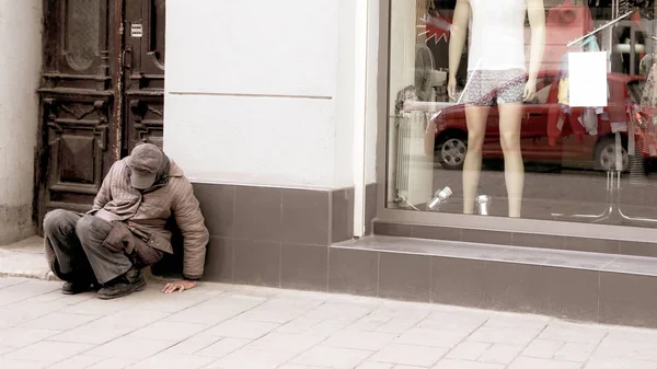 Obdachloser sitzt am Schaufenster des Ladens — Stockfoto