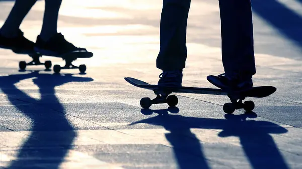 Silhouette of people riding on a skateboard in the sun — Stock Photo, Image