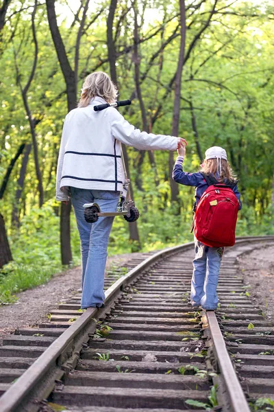 Young girl with a small child walking on railway tracks — Φωτογραφία Αρχείου