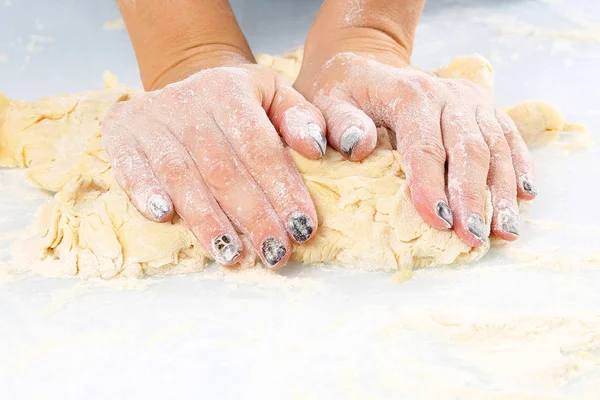 Les mains des femmes pétrissent la pâte sur un fond clair — Photo