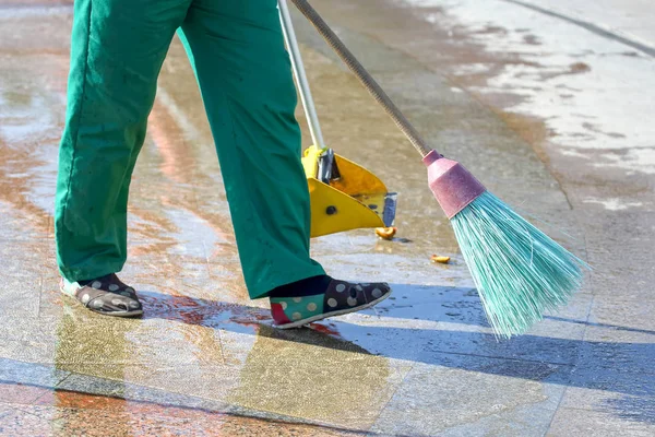 janitor cleans the sidewalk of the city from fallen leaves