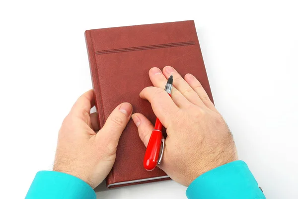 Manos sosteniendo un bolígrafo rojo y un cuaderno sobre fondo blanco —  Fotos de Stock