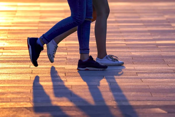 Legs of two people walking on the background of sunlight — Stock Photo, Image