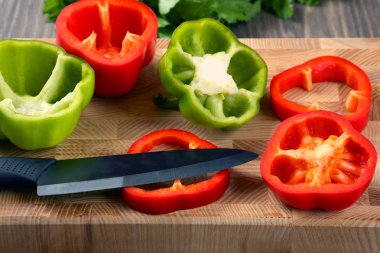 tatlı biber bir ahşap tahta üzerinde seramik bir bıçakla dilimlenmiş