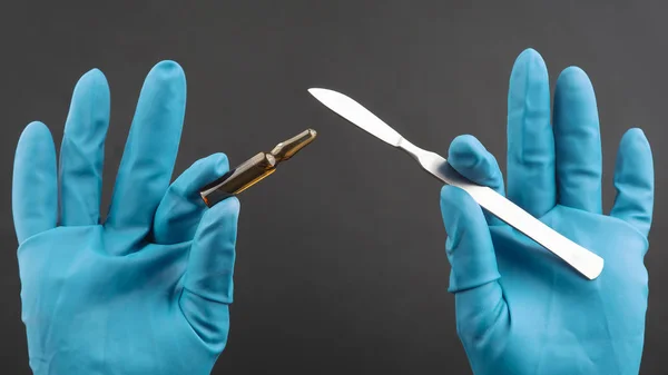 Lékařský skalpel a lahvička pro injekci v rukou s modrou GLO — Stock fotografie