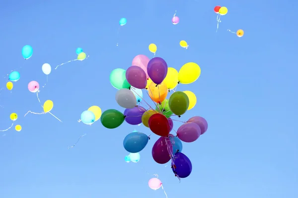 Muitos balões multicoloridos voando no céu azul — Fotografia de Stock
