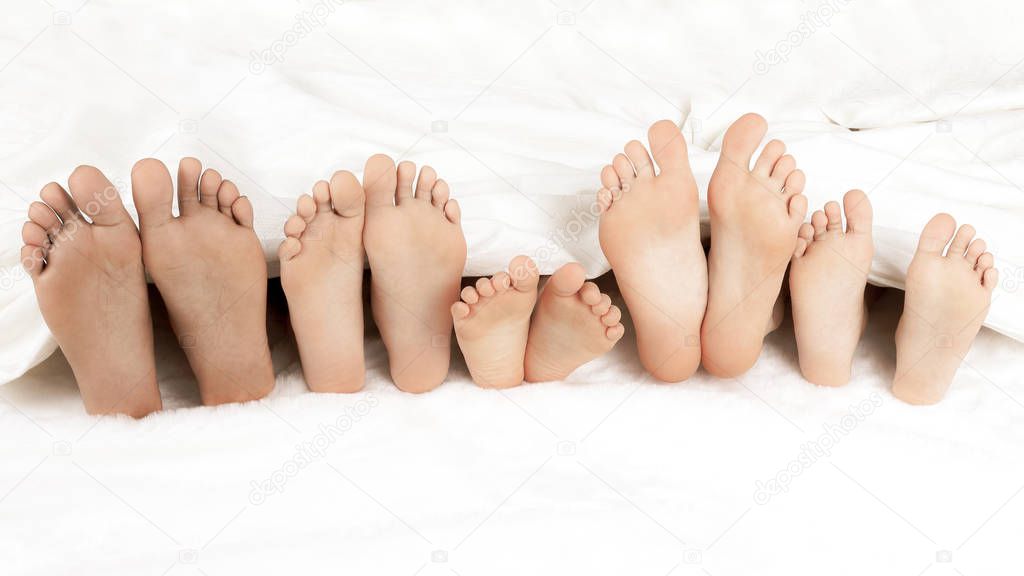 many children's feet peeking from under the blanket