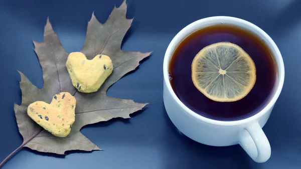 Cangkir teh putih dengan lemon di piring dengan kue dan daun lea musim gugur — Stok Foto