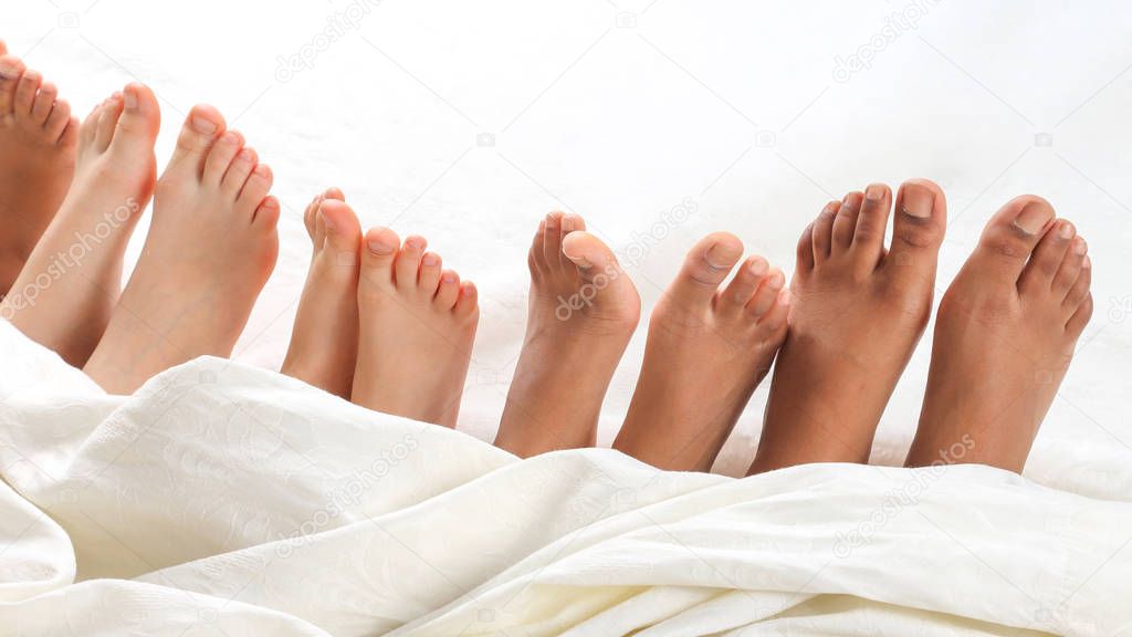 many children's feet peeking from under the blanket