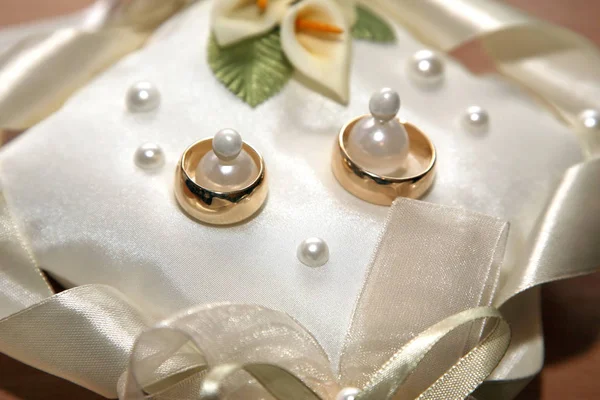 Anéis de casamento de ouro jazem em um travesseiro decorativo — Fotografia de Stock