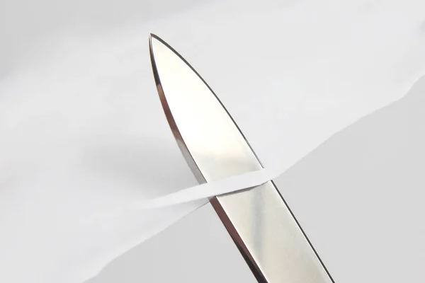 Lâmina de uma faca afiada cortada através do papel branco — Fotografia de Stock