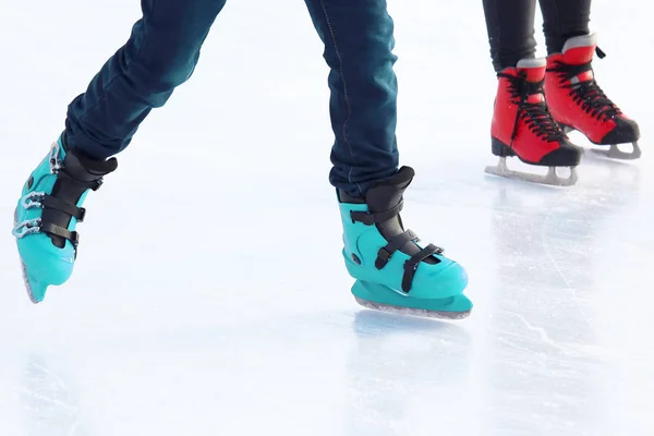 Fötter av olika människor skridskor på isbanan — Stockfoto