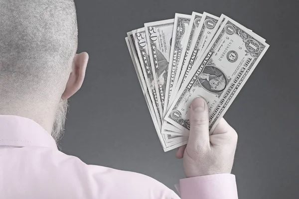 hand of a man in a shirt holding dollar bills