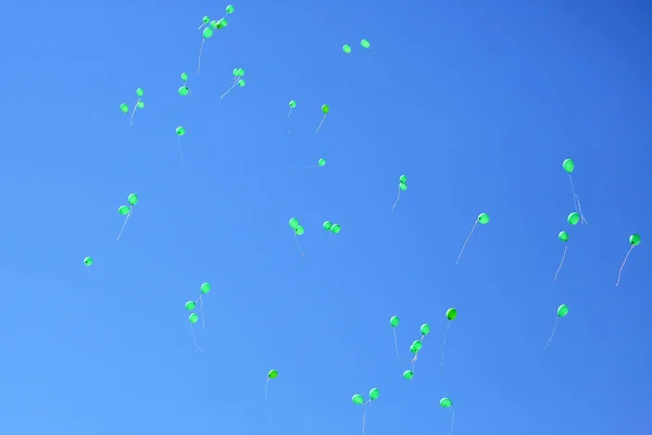 many green balloons flying in the blue sky