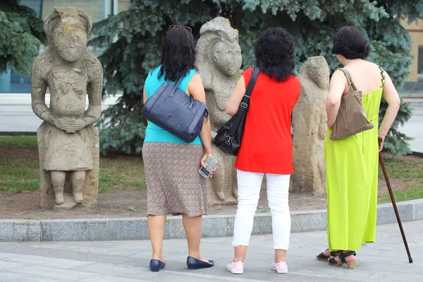 three women on a journey looking at three ancient human sculptur